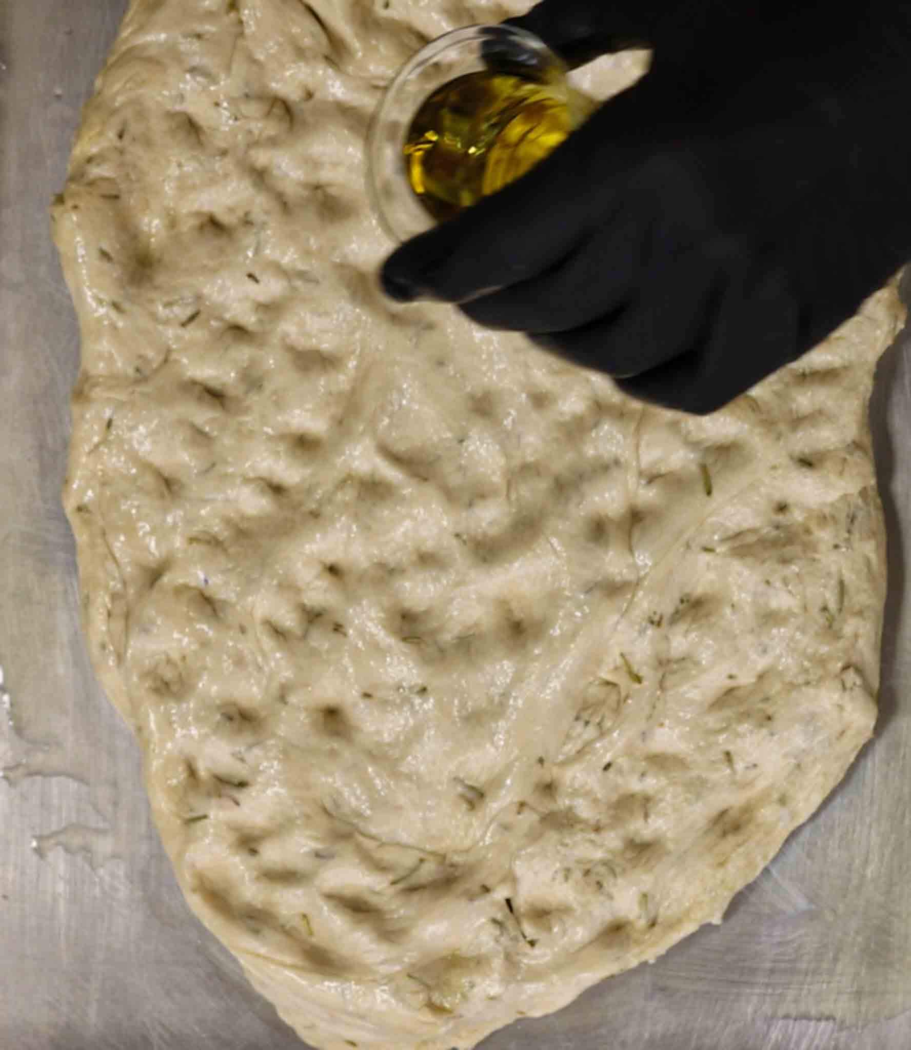 filling the focaccia dough with olive oil